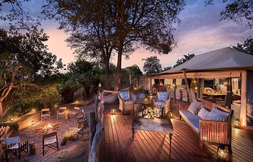 African Bush Camps Linyanti Bush Camp – mid-tier safari lodge in Botswana featuring outdoor deck, firepit, and tented accommodation under the African sunset.