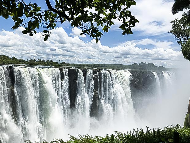 Victoria Falls thundering over the edge of the Zambezi River gorge during the wet season, a breathtaking natural wonder often featured in African safari itineraries through Zimbabwe.