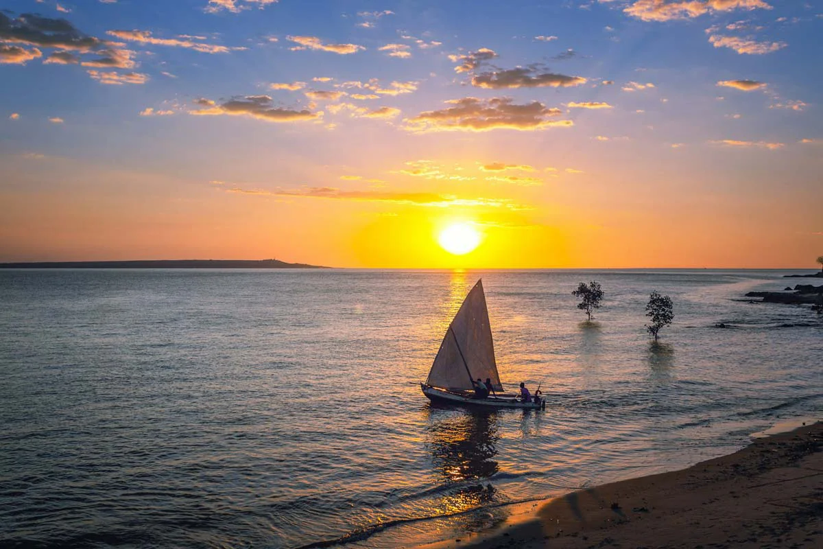 Traditional sailboat gliding through a calm lagoon at sunset on Madagascar’s Masoala Peninsula—an unforgettable African safari and photo tour moment with vibrant skies and serene waters.