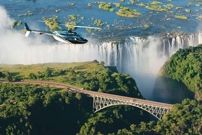 Helicopter flying over Victoria Falls and the Victoria Falls Bridge during a scenic Flight of Angels tour on an African safari.