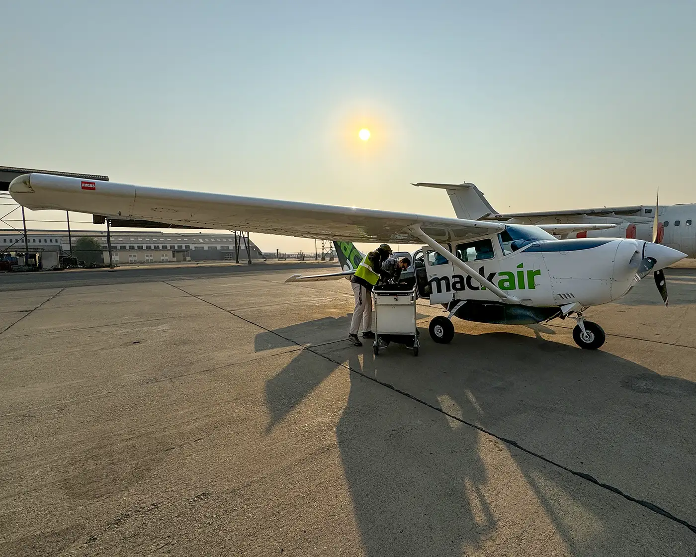 MacAir light aircraft being loaded on the runway at sunrise, preparing for an African safari air charter service in Zimbabwe.